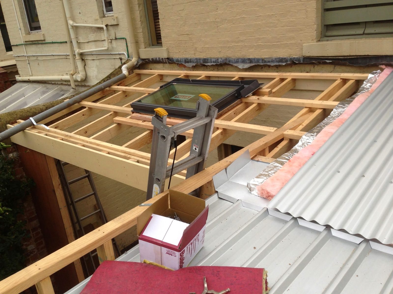 A skylight sitting in new timber roof framing beside metal roof sheeting and insulation